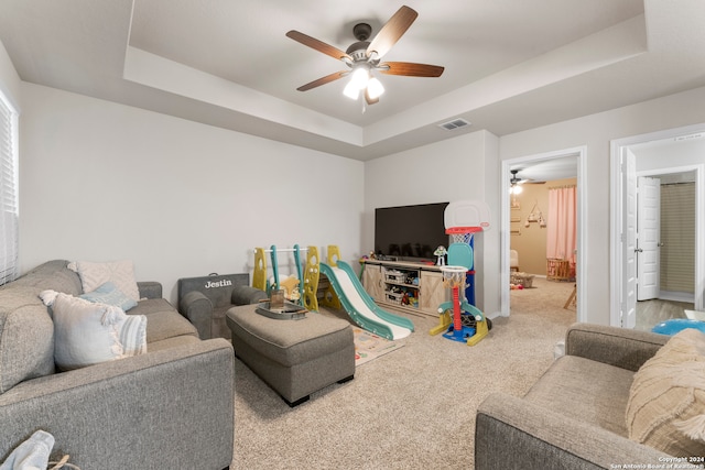 carpeted living room featuring ceiling fan and a tray ceiling