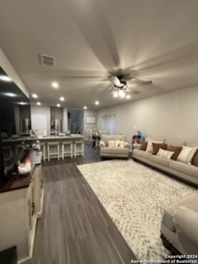 living room featuring ceiling fan and dark hardwood / wood-style floors