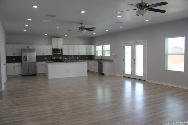 kitchen with white cabinetry, ceiling fan, backsplash, wood-type flooring, and appliances with stainless steel finishes