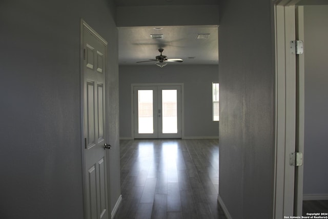 hall with french doors, a textured ceiling, and dark hardwood / wood-style floors