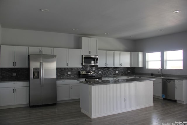 kitchen featuring stainless steel appliances, dark wood-type flooring, sink, white cabinets, and a center island