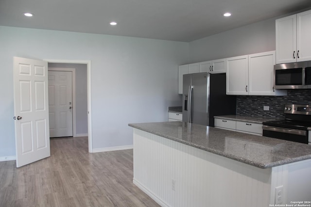 kitchen with backsplash, dark stone counters, white cabinets, light wood-type flooring, and stainless steel appliances