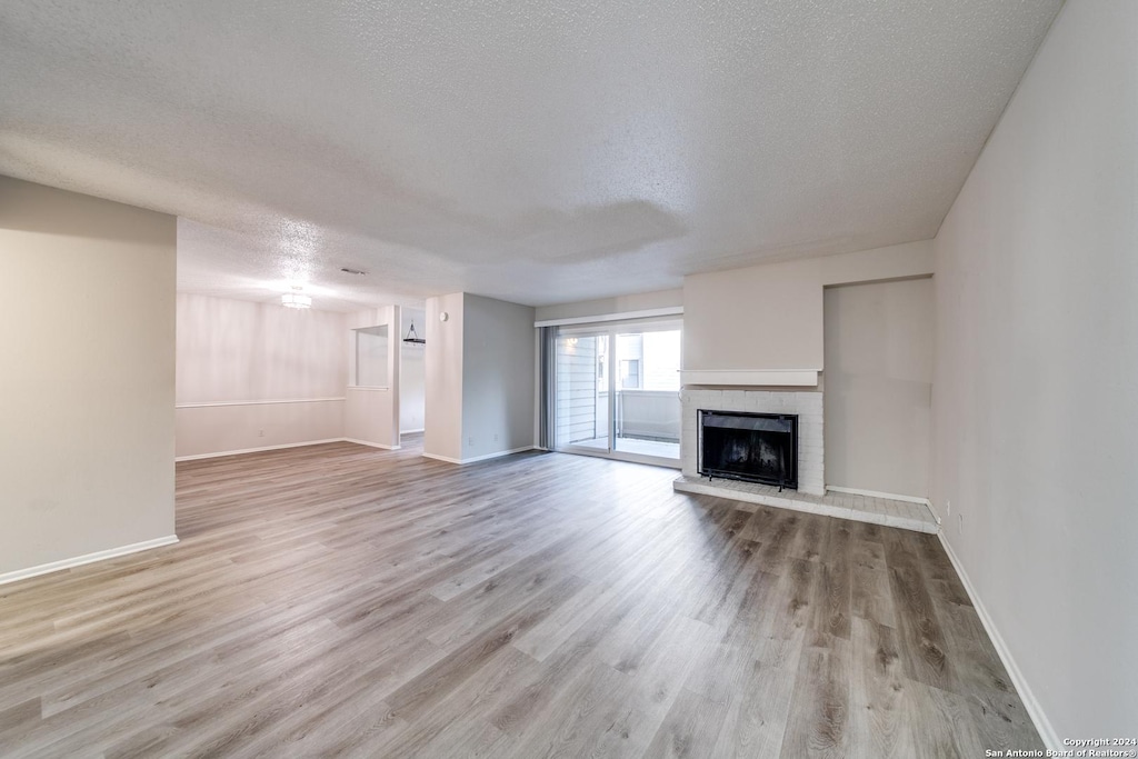 unfurnished living room featuring a textured ceiling, a fireplace, and light wood-type flooring