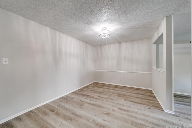 unfurnished room with a textured ceiling and light hardwood / wood-style flooring