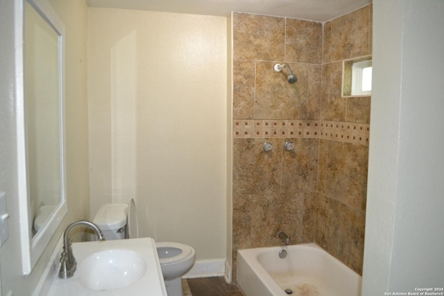 full bathroom featuring toilet, tiled shower / bath, and sink