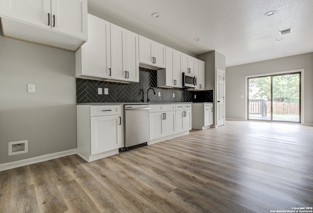 kitchen featuring white cabinetry, tasteful backsplash, light hardwood / wood-style flooring, and stainless steel appliances