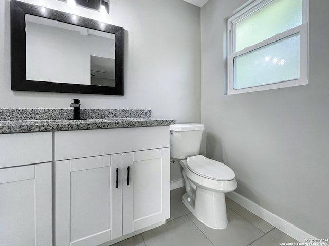 bathroom with toilet, vanity, and tile patterned floors