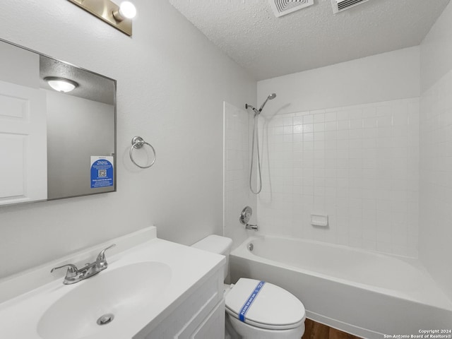 full bathroom featuring vanity, a textured ceiling, tiled shower / bath combo, hardwood / wood-style floors, and toilet