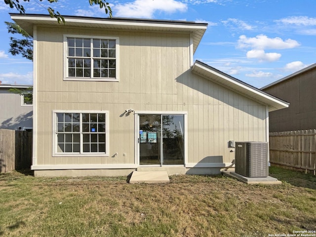 rear view of property with central AC and a yard