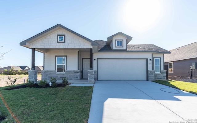 craftsman-style house with a garage, covered porch, driveway, stone siding, and a front yard