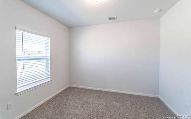 carpeted empty room with visible vents and baseboards