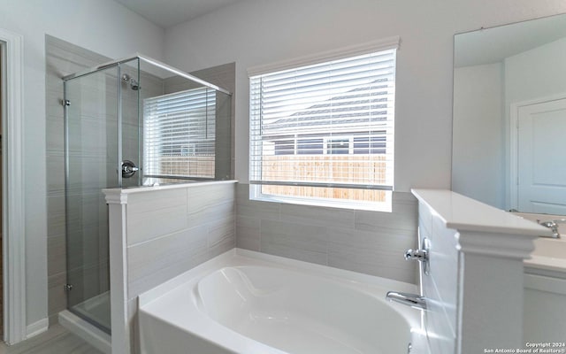 bathroom featuring a stall shower, vanity, and a bath