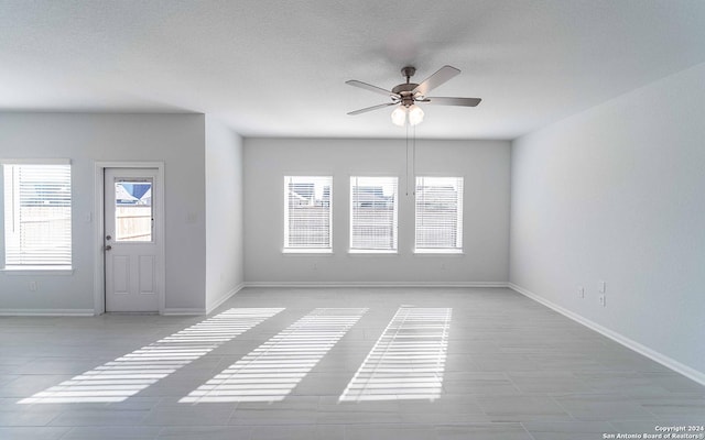 entryway with a ceiling fan, a textured ceiling, and baseboards