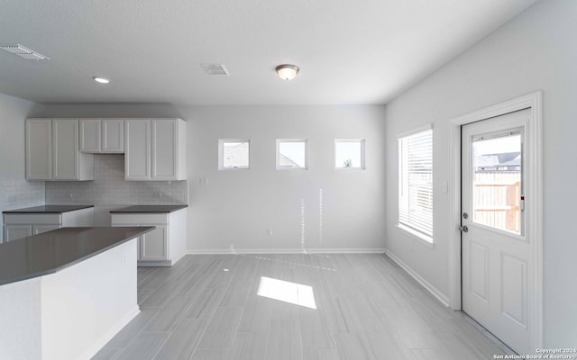 kitchen with baseboards, dark countertops, visible vents, and decorative backsplash