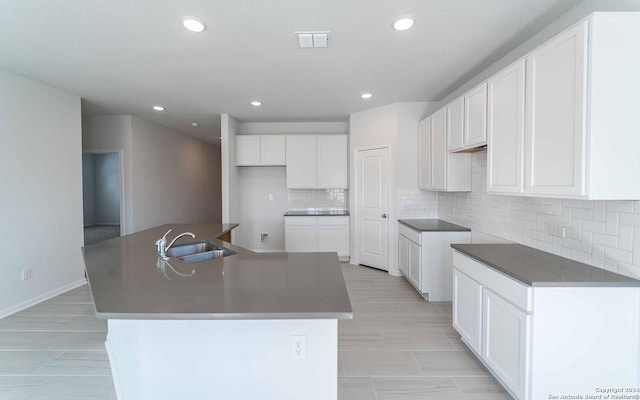 kitchen with white cabinets, a sink, and an island with sink