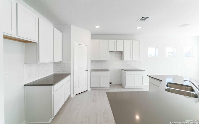 kitchen with white cabinets, visible vents, and a sink