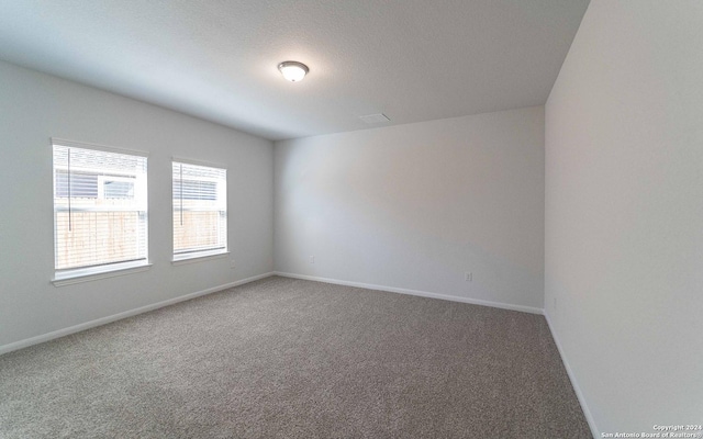 unfurnished room featuring carpet floors, baseboards, and a textured ceiling