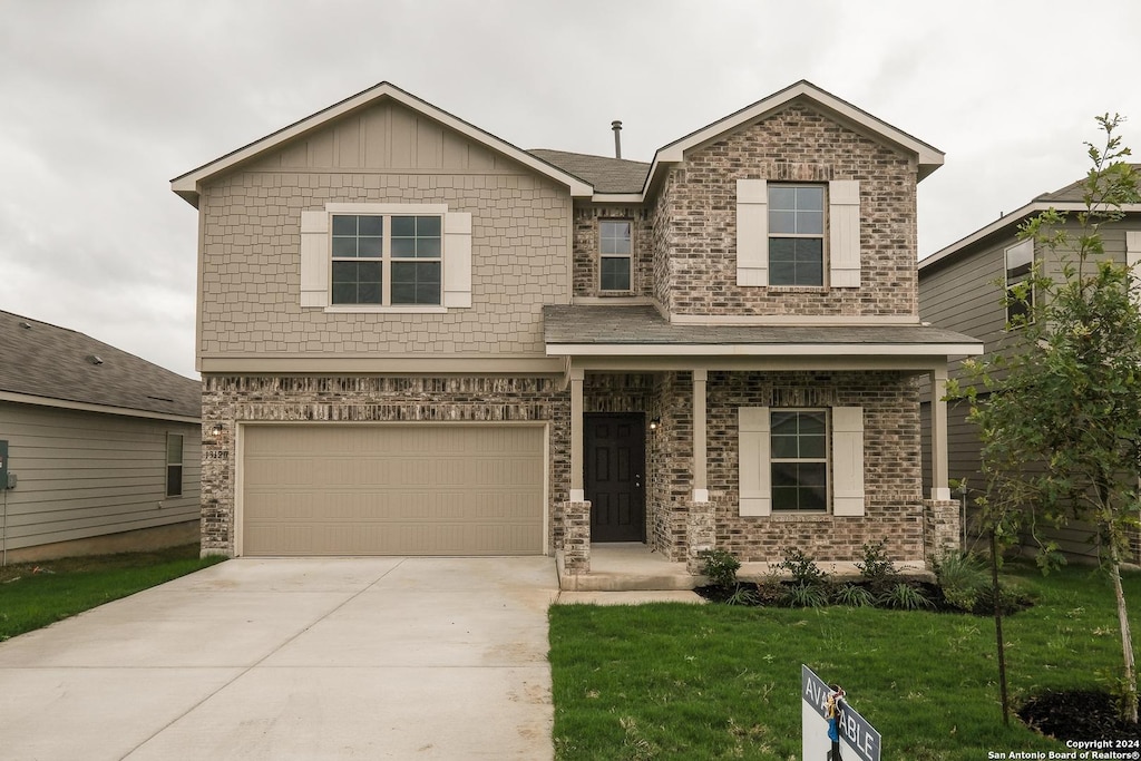 view of front of home featuring driveway, brick siding, an attached garage, and a front yard