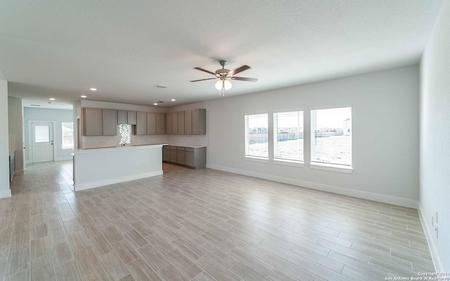 unfurnished living room with baseboards, light wood-type flooring, recessed lighting, a textured ceiling, and a ceiling fan