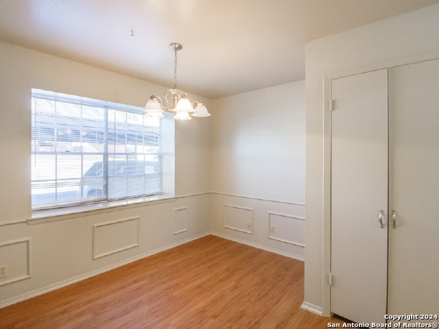 unfurnished dining area featuring light wood-type flooring and an inviting chandelier