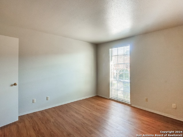 unfurnished room featuring hardwood / wood-style flooring and a textured ceiling