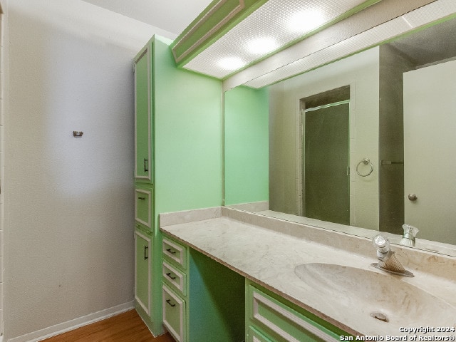 bathroom with hardwood / wood-style floors, vanity, and an enclosed shower