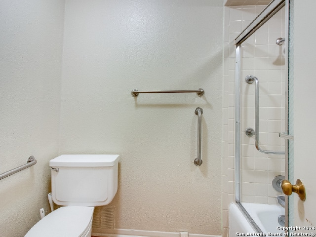 bathroom featuring enclosed tub / shower combo and toilet