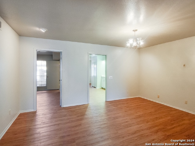 unfurnished room featuring a chandelier and wood-type flooring