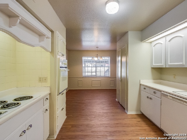 kitchen with pendant lighting, oven, light hardwood / wood-style flooring, white cabinetry, and a chandelier