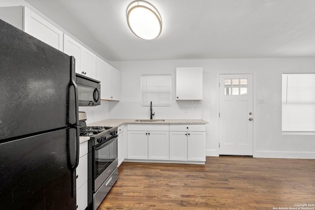 kitchen featuring sink, white cabinetry, dark wood-type flooring, and black appliances