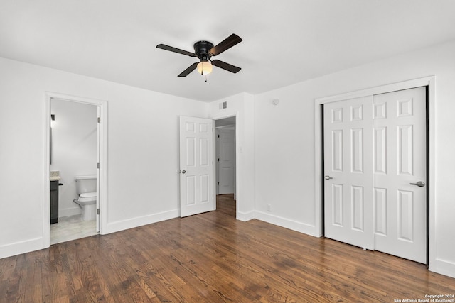 unfurnished bedroom featuring ensuite bathroom, ceiling fan, dark hardwood / wood-style flooring, and a closet