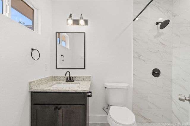 bathroom with a tile shower, vanity, and toilet