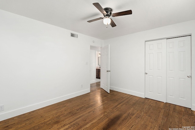 unfurnished bedroom featuring ceiling fan, a closet, and dark wood-type flooring