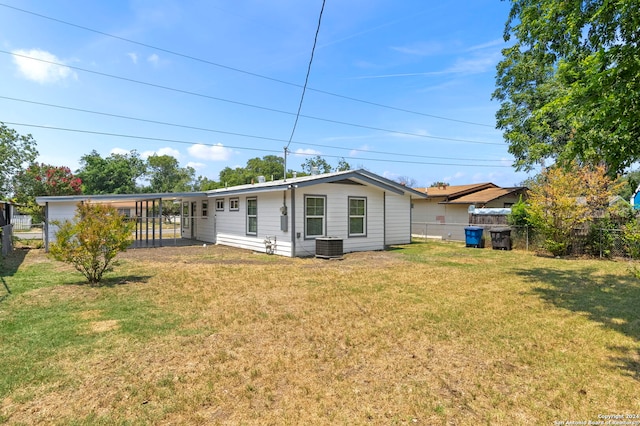 back of property with a lawn, central AC unit, and a carport