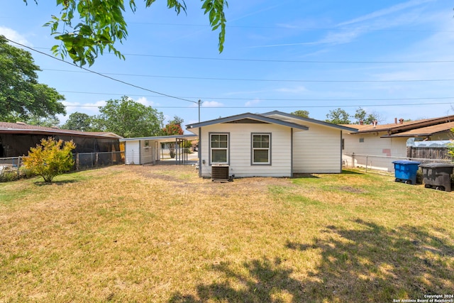 back of property with a lawn and central AC