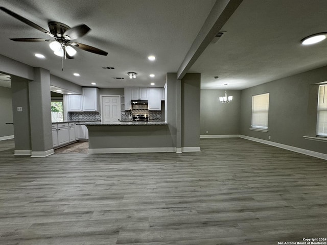 kitchen featuring white cabinets, light wood-type flooring, tasteful backsplash, and ceiling fan with notable chandelier