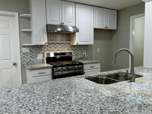 kitchen featuring light stone countertops, tasteful backsplash, gas range, sink, and white cabinetry