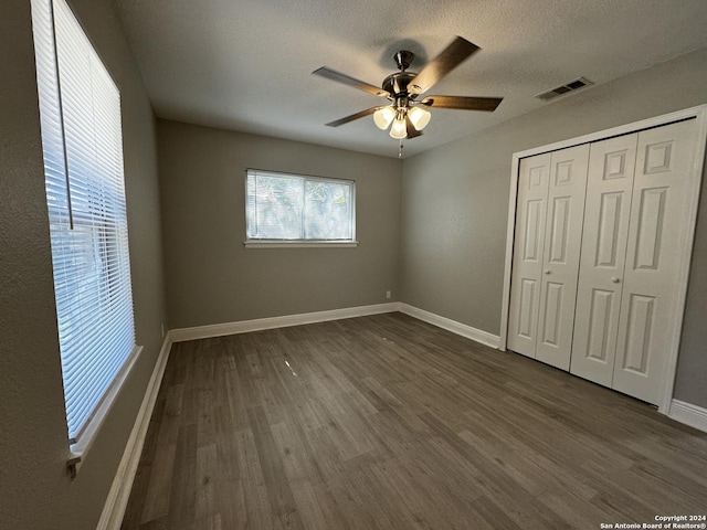 unfurnished bedroom featuring a closet, ceiling fan, dark hardwood / wood-style flooring, and a textured ceiling