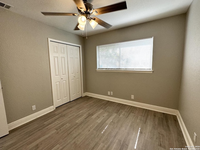 unfurnished bedroom with ceiling fan, dark wood-type flooring, and a closet