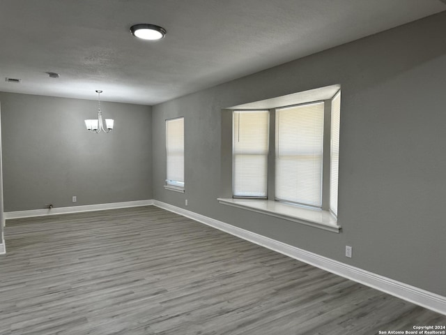 unfurnished room with wood-type flooring and a notable chandelier