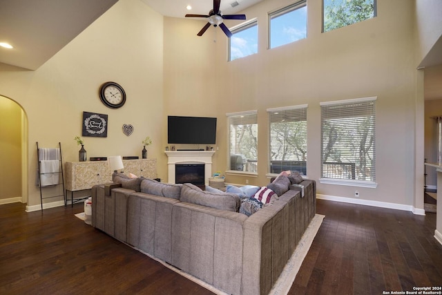 living room with ceiling fan, dark hardwood / wood-style floors, and a high ceiling