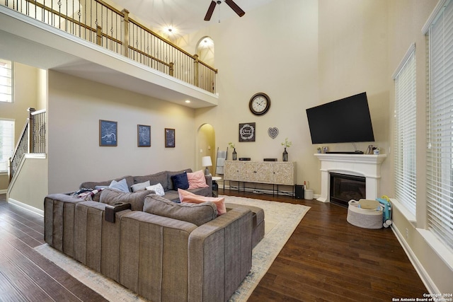 living room featuring ceiling fan, a towering ceiling, and dark wood-type flooring