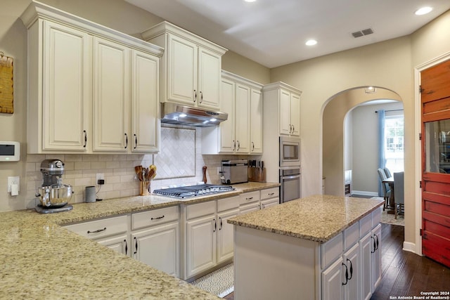 kitchen featuring tasteful backsplash, light stone countertops, dark wood-type flooring, and appliances with stainless steel finishes