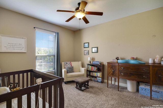 carpeted bedroom featuring a nursery area and ceiling fan