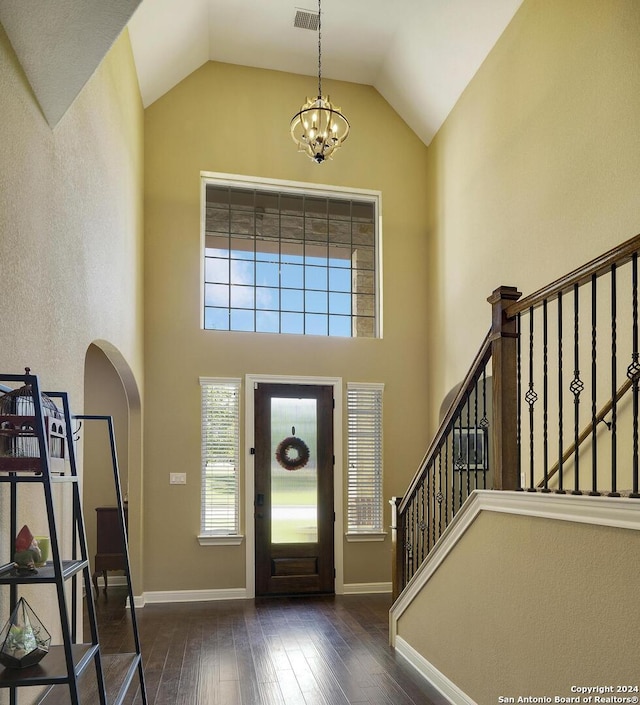 entrance foyer with dark hardwood / wood-style flooring, high vaulted ceiling, and a chandelier