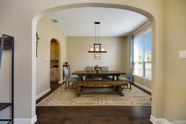 dining room with dark hardwood / wood-style floors and an inviting chandelier