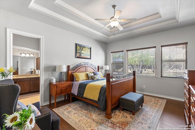 bedroom with connected bathroom, ceiling fan, dark wood-type flooring, crown molding, and a tray ceiling