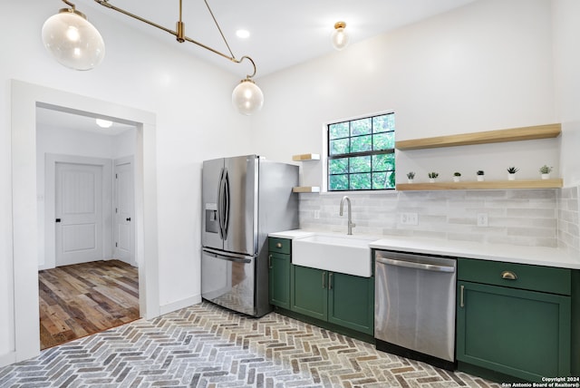 kitchen with backsplash, hanging light fixtures, appliances with stainless steel finishes, and light hardwood / wood-style floors