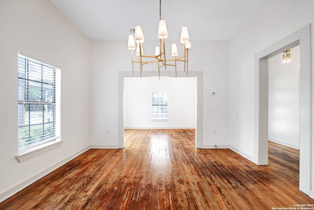 unfurnished dining area featuring wood-type flooring and a chandelier