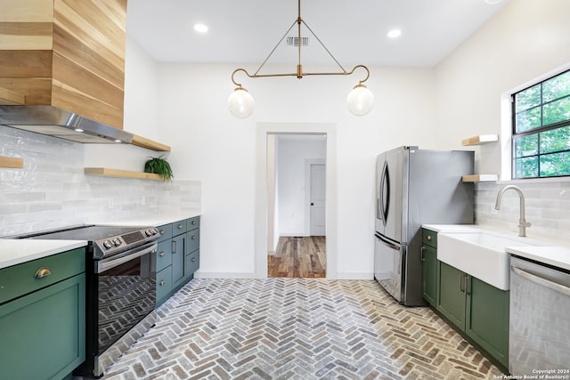 kitchen with appliances with stainless steel finishes, green cabinetry, wall chimney exhaust hood, sink, and tasteful backsplash